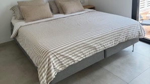 A modern bedroom with a bed, a bedside table, a wall-mounted shelf, and a large window. - Luxurious Apartment in Puerto Banus Marbella (Marbella)