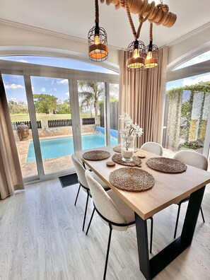 A dining area with a wooden table, woven placemats, and a Buddha statue. - Casa Bonita Sleeps 4 With Private Pool (Torre-Pacheco)