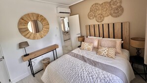 A bedroom with a bed, bedside lamps, a wooden headboard, a round mirror, and a wall art piece. - Casa Bonita Sleeps 4 With Private Pool (Torre-Pacheco)
