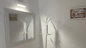 Una stanza angolare con un appendiabiti, uno specchio e un quadro appeso al muro.