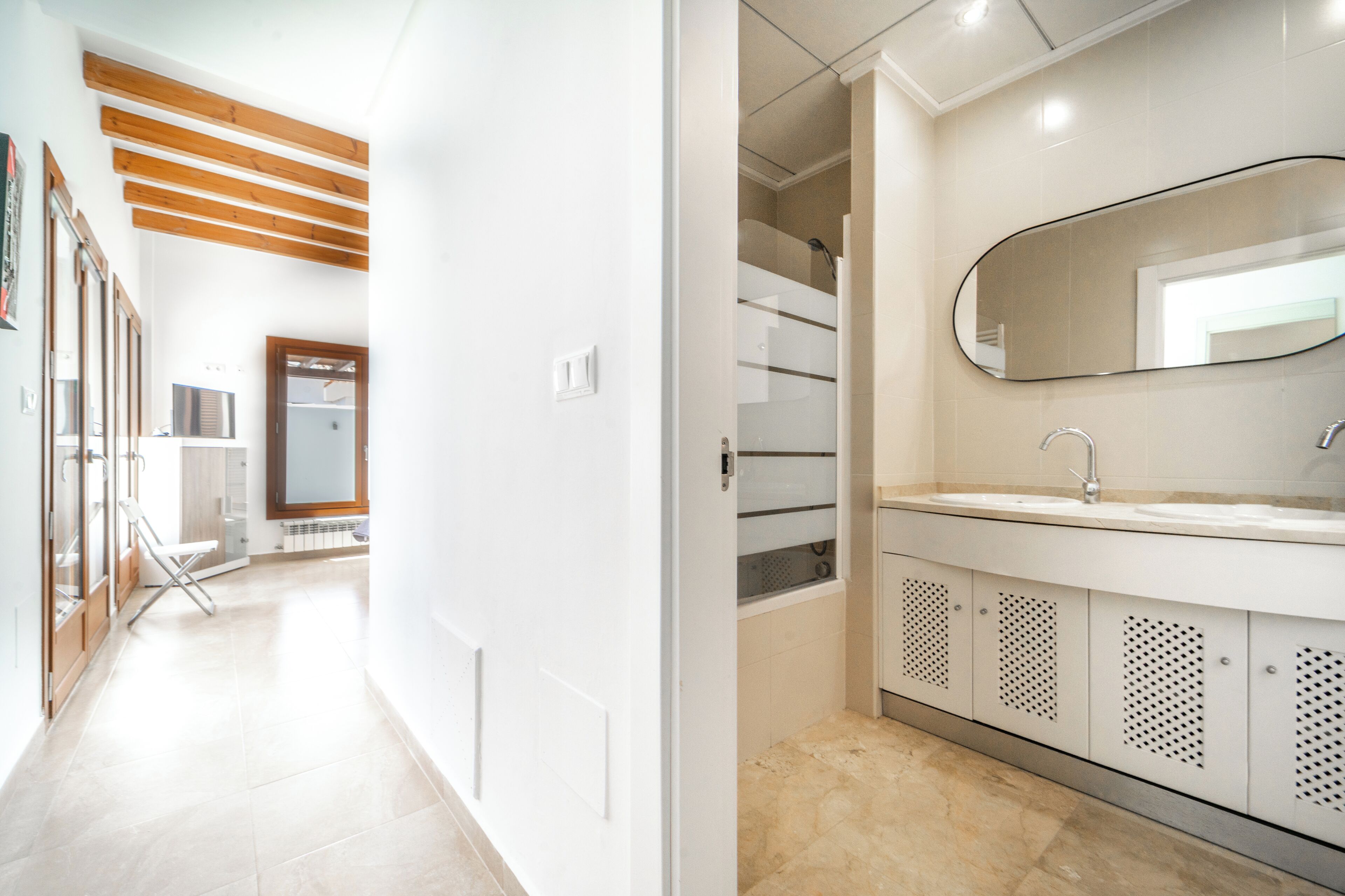 A modern bathroom with a large mirror, a sink, and a shower area.