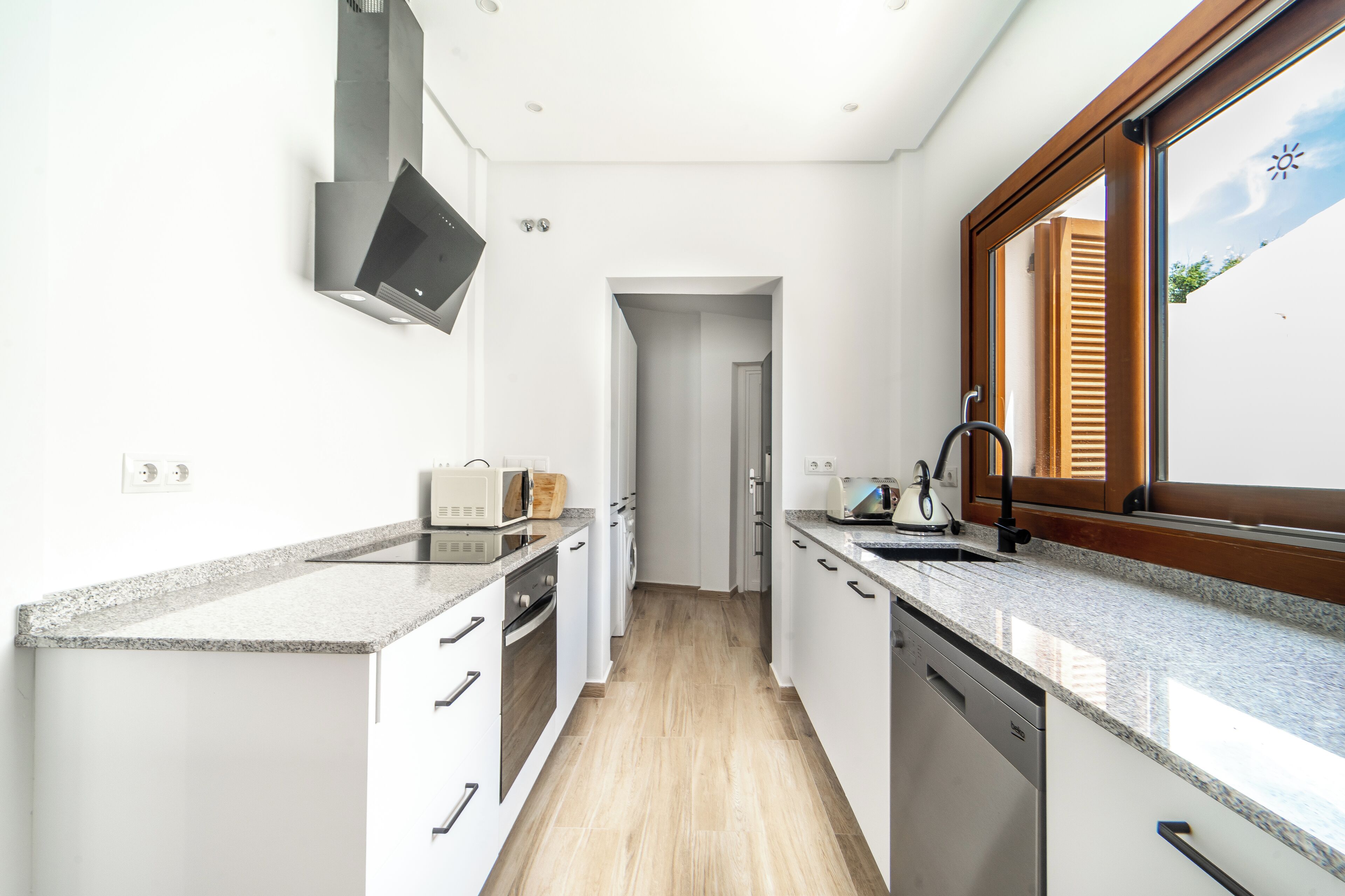 A modern kitchen with white cabinetry, granite countertops, and a built-in oven.