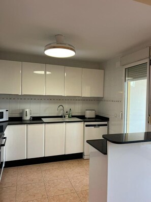 A modern kitchen with white cabinets, a black countertop, a built-in oven, and a sink. - 2-bed Apartament Rosaleda Monterey (Denia)
