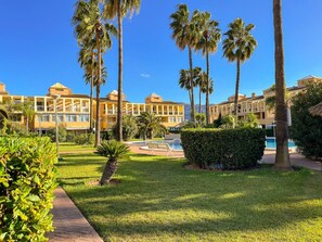 A resort with multiple yellow buildings, palm trees, a swimming pool, and well-maintained lawns. - 2-bed Apartament Rosaleda Monterey (Denia)