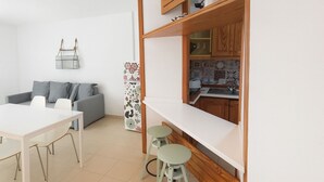 Un espacio habitable compacto con kitchenette, zona de comedor y área de descanso.