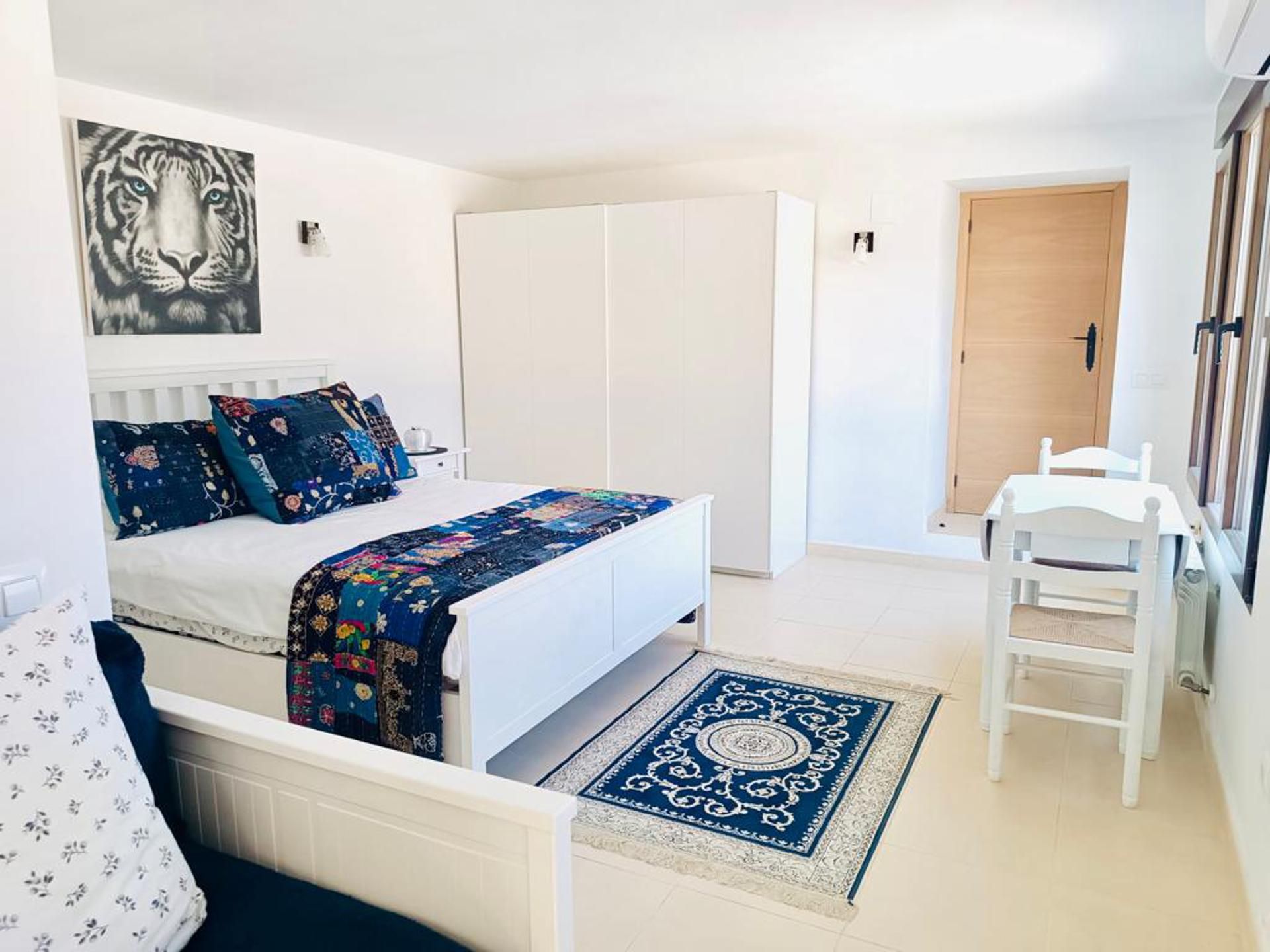 Un dormitorio con cama, escritorio, silla, armario y puerta.