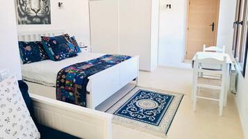 Un dormitorio con cama, escritorio, silla, armario y puerta.