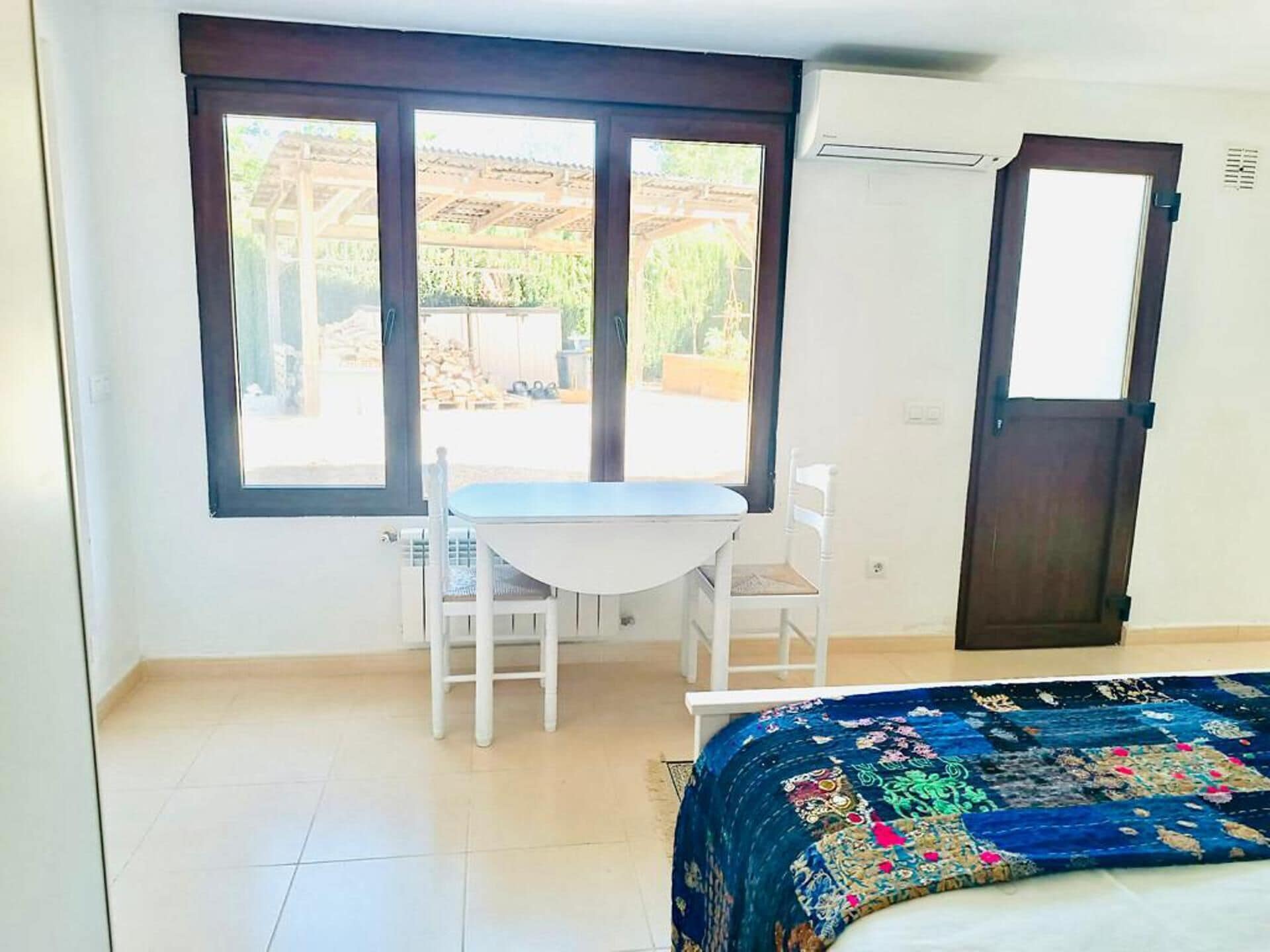 A room with a bed, a table, two chairs, a window, and a door.