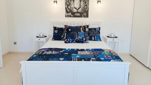 A bedroom with a white bed, a tiger painting on the wall, and two bedside tables with lamps. - Moraira Escape With Private Pool, 1 Bed, Sleeps 2 (Teulada)