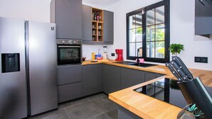 A modern kitchen with grey cabinets, a stainless steel refrigerator, a built-in oven, and a wooden countertop. - Gorgeous Newly Renovated 4-bedroom Villa! (Yaiza)