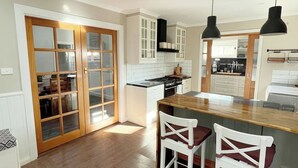 A modern kitchen with wooden flooring, white cabinets, a central island, and two bar stools.