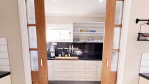 A kitchen with white cabinets, a wooden countertop, and a black backsplash.
