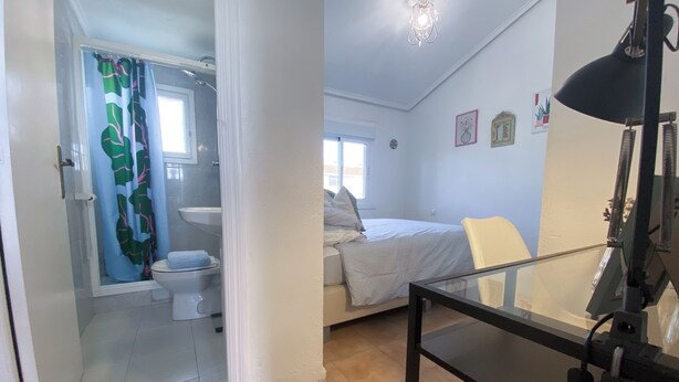 Une chambre à coucher avec un lit, une table de chevet, une lampe et une fenêtre.