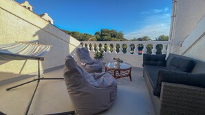 Une terrasse sur le toit, aménagée avec un espace salon comprenant un canapé, deux fauteuils poire et une petite table sur laquelle est posée une plante.