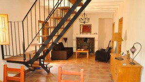Un salon avec un escalier en bois, une cheminée, un canapé, une table basse et un meuble en bois.