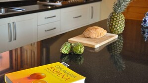 Une cuisine avec un livre intitulé « Culinaria España » posé sur le comptoir, un ananas et des artichauts.