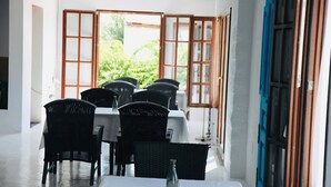 A dining area with tables and chairs, large windows, and a view of greenery outside. - 18 Person Bachelorette Pool Parties (Coin)