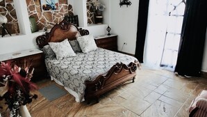 A bedroom with a large bed, a stone wall, a window with a view, and a vase with flowers. - 18 Person Bachelorette Pool Parties (Coin)