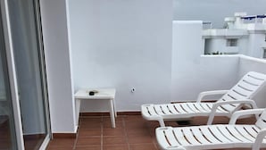 A balcony with white lounge chairs, a small table, and a white wall. - Beautiful 4 Bedroom Duplex Apartment (Estepona)