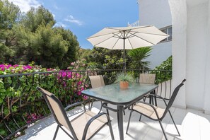 Un patio con tavolo e sedie in vetro, un ombrellone e una pianta in vaso.