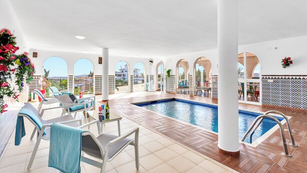 An indoor swimming pool with lounge chairs and a view of the city. - Most Luxurious Villa on the Costa del Sol (Mijas)