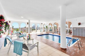 An indoor swimming pool with lounge chairs and a view of the city. - Most Luxurious Villa on the Costa del Sol (Mijas)