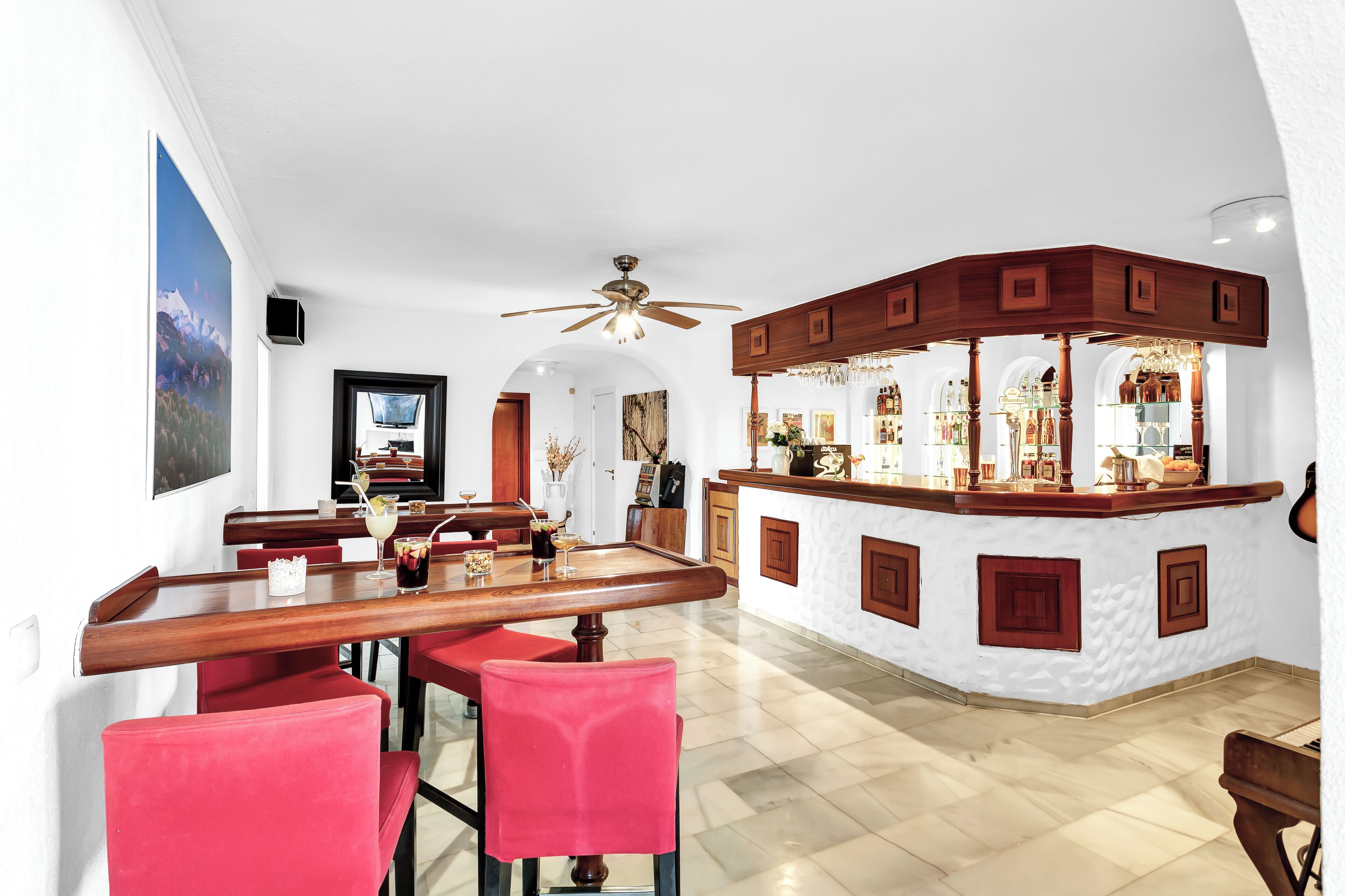 Un comedor espacioso con barra de madera y sillas rojas.