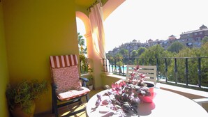 Un balcon avec une chaise, une table et des plantes en pot.