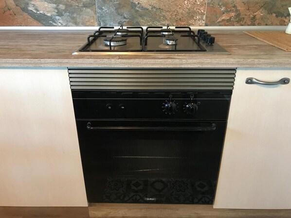 A compact kitchen with a gas stove, oven, and integrated dishwasher. - Aurora 2-bed Cottage - Sleeps 4 - Montseny Park (Arbucies)