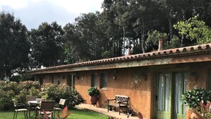 Un bâtiment de style rustique, doté d’un toit en tuiles, d’un patio couvert avec des meubles d’extérieur et d’un jardin bien entretenu.