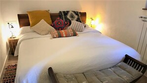 Un lit bien fait, agrémenté de plusieurs coussins et d’un banc placé au pied du lit.