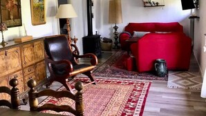 Un salon chaleureux avec un canapé rouge, un fauteuil en bois et un tapis à motifs.