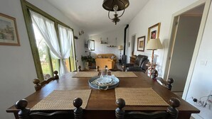 Un coin repas avec une table et des chaises en bois, un lustre et une vue sur l’extérieur.