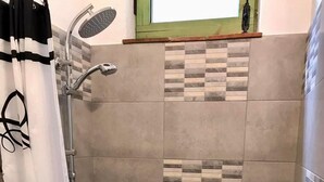 Ein Duschbereich mit Regendusche, Handtuchhalter und einer Flasche Duschgel an der Wand.