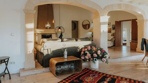 Ein Schlafzimmer mit einem Bett, einem Holznachttisch, einer Vase mit Blumen und einer bogenförmigen Tür.
