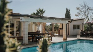 Ein Poolbereich mit Pergola, Gartenmöbeln und Blick auf den Pool.