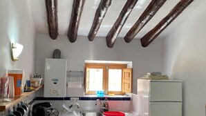 Egy kis méretű konyha, amelyben van egy ablak, egy mosogató és egy hűtőszekrény.