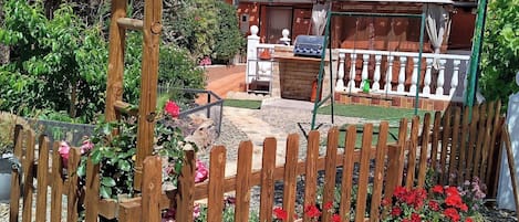 A wooden fence, a patio area with a grill, and a house with a tiled roof.