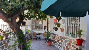 Un patio con pared de piedra, plantas en macetas y mobiliario exterior.