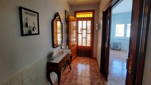 Un pasillo con una puerta de madera, un espejo y un cartel enmarcado en la pared.