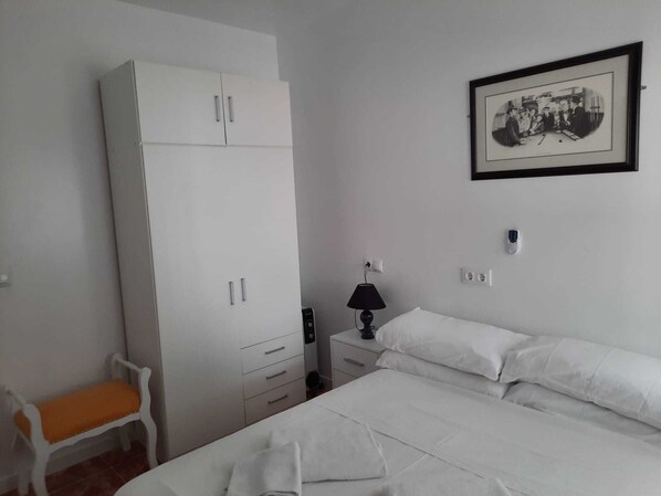 A bedroom with a bed, a white wardrobe, a chair, a bedside table with a lamp, and a framed picture on the wall. - Comfortable 3-bed House, Bungalow (San Javier)