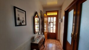 Un pasillo con una puerta de madera, un espejo y un cartel enmarcado con llaves.