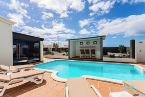 A swimming pool with lounge chairs, a small building with a bar area, and a clear blue sky. - 3 Bed Villa - Pool, Bbq, Terrace w Sea Views (Yaiza)