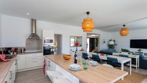 Una cucina moderna con mobili bianchi, un'isola in legno e un'area pranzo con tavolo e sedie.