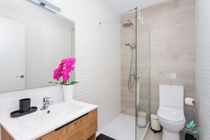 A modern bathroom with a white sink, a mirror, a glass shower enclosure, and a toilet. - Remarkable 5-bed Villa in Playa Blanca (Yaiza)
