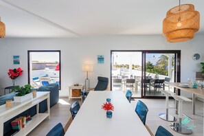 A modern living room with a dining area, large windows, and a view of the outdoors. - Remarkable 5-bed Villa in Playa Blanca (Yaiza)