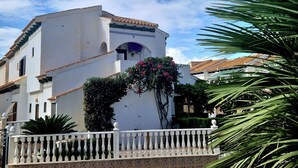 A white building with a tiled roof, a balcony with white balustrades, and a small archway. - Lovely Apartment Near the Beach in Sunny La Mata (Torrevieja)