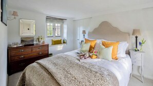 Un dormitorio ordenado con una cama grande, un aparador, una ventana y una mesita de noche.