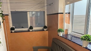 Una habitación pequeña y acogedora con un banco, una ventana con persianas y una planta en el alféizar.