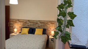Un dormitorio con una cama, dos lámparas de noche, un estante en la pared y una planta en maceta.